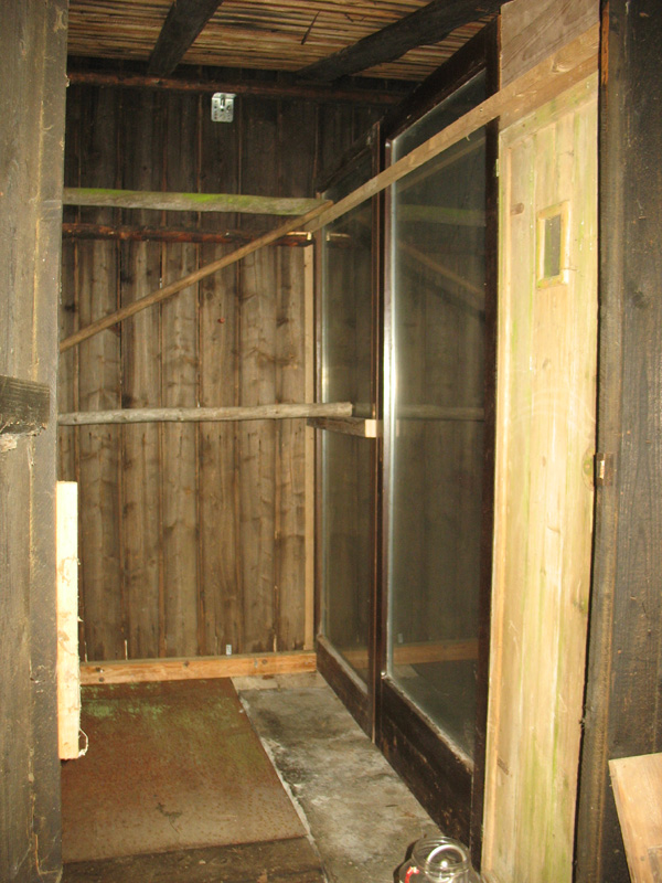 Trennwand aus alten Balkontüren und Holzresten.